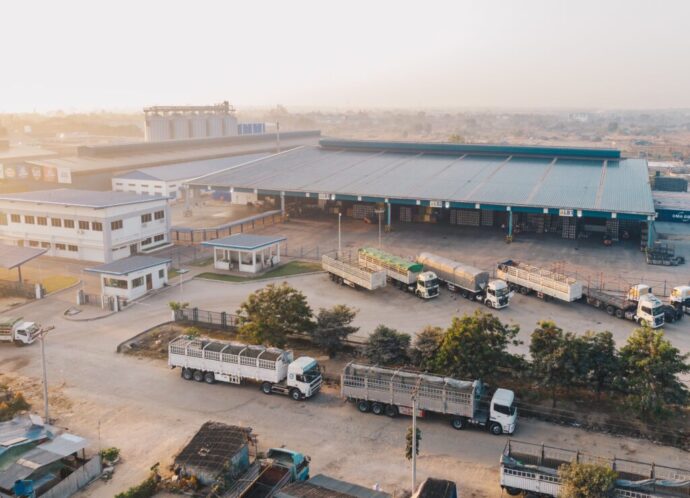 Aerial shot of factory trucks parked near the warehouse at daytime Aerial shot of factory trucks parked near the warehouse at daytime
